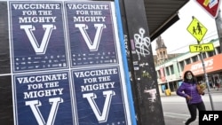 FILE - A person walks past posters encouraging people to get vaccinated in Melbourne on Aug. 31, 2021.