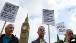 FILE - Demonstrators supporting Polish workers hold banners at a rally in Westminster, London, Aug. 20, 2015. Britain's new government wants to see curbs on employers hiring foreign workers and tightening tests on companies that want to recruit overseas.