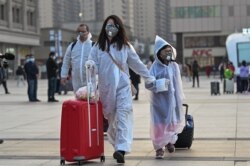 eople wearing protective clothing and masks arrive at Hankou Railway Station in Wuhan, to board one of the first trains leaving the city in China's central Hubei province early on April 8, 2020.