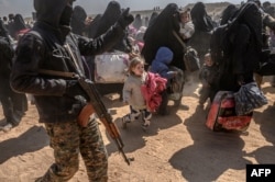 FILE - Women and children evacuated from the Islamic State group's embattled holdout of Baghuz arrive at a screening area held by the U.S.-backed Kurdish-led Syrian Democratic Forces, in the eastern Syrian province of Deir el-Zour, March 6, 2019.