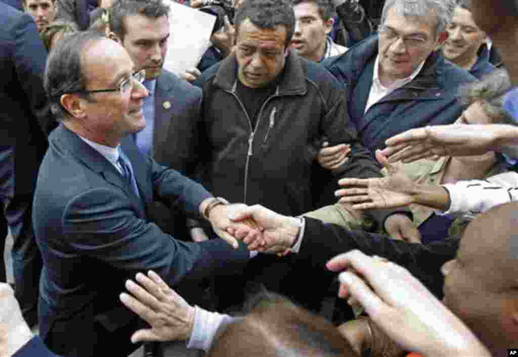 President-elect Francois Hollande shakes hand with supporters as he leaves his campaign headquarters in Paris, Wednesday May 9, 2012. After winning the French Presidential Election, Hollande seems set to embark on a whirl-wind introduction to internation