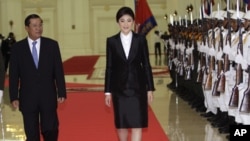 Cambodia's Prime Minister Hun Sen, left, walks together with Thai counterpart Yingluck Shinawatra, center, as she reviews an honor guard inside the Peace Palace in Phnom Penh, Cambodia, Thursday, Sept. 15, 2011