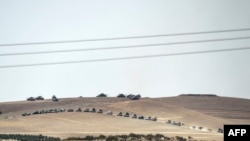 This picture taken from the Turkish Syrian border city of Karkamis in the southern region of Gaziantep, on Aug. 24, 2016 shows Turkish army tanks and pro-Ankara Syrian opposition fighters moving two kilometres west from the Syrian Turkish border town of J