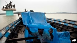 An Indian boatman uses a plastic sheet to protect himself from the rain, on the river Brahmaputra in Gauhati, India, May 30, 2017. Several northeastern Indian states experienced heavy rainfall as an effect of tropical Cyclone Mora that lashed southern Ban