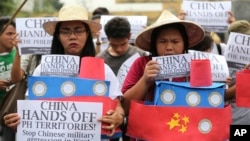 Filipino student activists hold mock Chinese ships to protest recent island-building and alleged militarization by China off the disputed Spratlys group of islands in the South China Sea during a rally near the Malacanang presidential palace in Manila, Ph