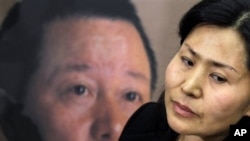 Geng He, wife of disappeared Chinese human rights lawyer Gao Zhisheng, seen on poster at rear, is interviewed before a news conference with Rep. Chris Smith, R-N.J., on Capitol Hill in Washington, Tuesday, Jan. 18, 2011, where he called attention to human