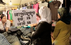 FILE- Shoppers speak to a sales clerk at a local market, in Phnom Penh, Cambodia, on June 26, 2013.