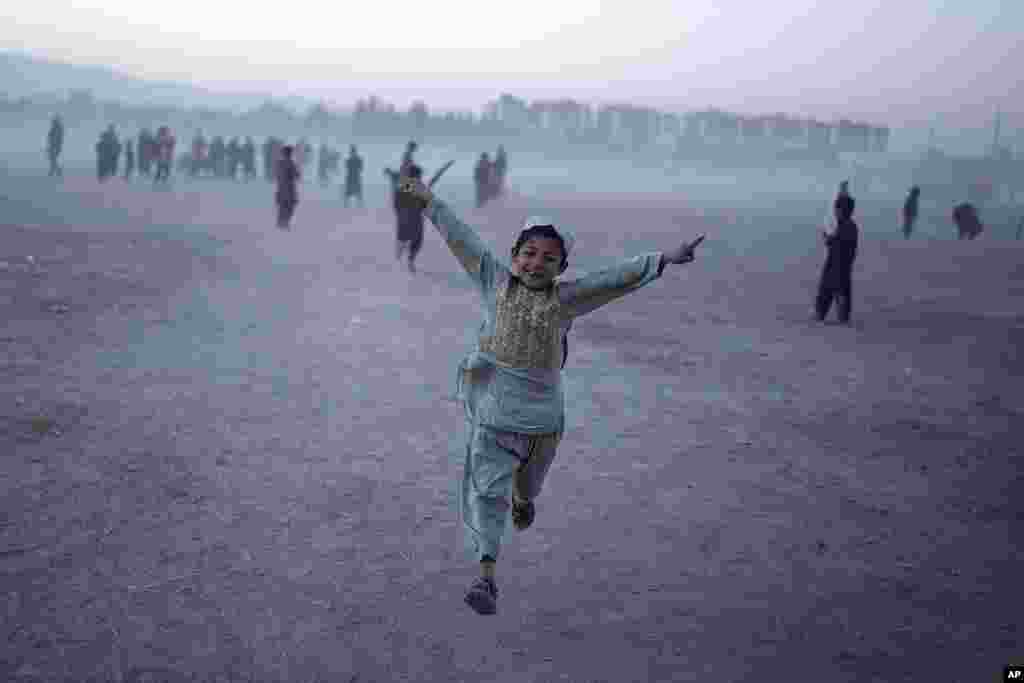 A young boy celebrates as he plays cricket with his friends in Chaman-e-Hozori park, Kabul, Afghanistan.