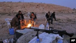 Libyan anti-government fighters sit by a fire to stay warm as they control a checkpoint on the outskirts of the southwestern town of Nalut, Libya, February 28, 2011