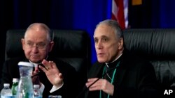 El cardenal Daniel DiNardo, derecha, presidente de la Conferencia de Obispos Católicos de EE.UU., y José Gómez, arzobispo de Los Ángeles, se aprestan a iniciar la sesión matutina de la reunión del organismo en Baltimore, martes 11 de junio de 2019. 