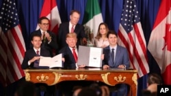 President Donald Trump, center, sits between Canada's Prime Minister Justin Trudeau, right, and Mexico's President Enrique Pena Nieto after they signed a new U.S.-Mexico-Canada Agreement that is replacing the NAFTA trade deal. 