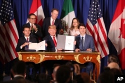 FILE - President Donald Trump sits between Canada's Prime Minister Justin Trudeau, right, and Mexico's then-president, Enrique Pena Nieto, after they signed the U.S.-Mexico-Canada Agreement that is replacing the NAFTA trade deal.