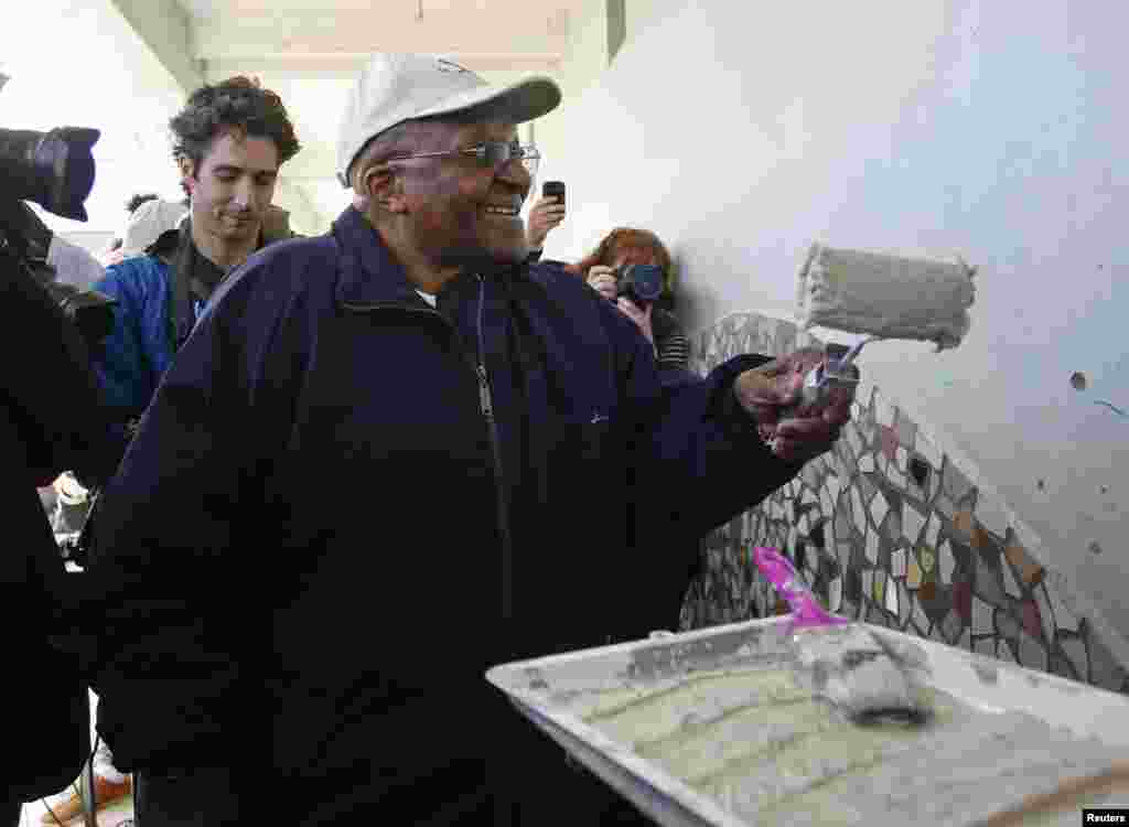 O Arcebispo emérito Desmond Tutu celebra o "Dia de Mandela" pintando uma parede de uma escola primária na cidade do Cabo.