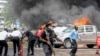 FILE - People extinguish car fires caused by a bomb blast near Parliament in Kampala, Uganda, Nov. 16, 2021. Police on Nov. 18 said authorities killed at least five people accused of having ties to the group responsible for the bombings on Nov. 16.