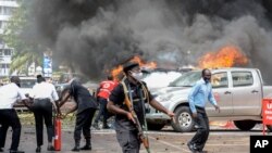 FILE - People extinguish car fires caused by a bomb blast near Parliament in Kampala, Uganda, Nov. 16, 2021. Police on Nov. 18 said authorities killed at least five people accused of having ties to the group responsible for the bombings on Nov. 16.