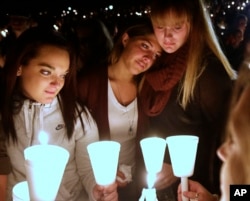 Umpqua Community College students Nicole Zamarripa, left, Kristen Sterner, center and Carrissa Welding, right, join others at Stewart Park, in Roseburg, Ore., for a candlelight vigil for those killed during a fatal shooting at the school, Oct. 1, 2015.
