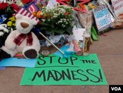 Among the tributes honoring Dallas shooting victim outside Dallas police headquarters, a sign urges the country to “Stop the madness,” July 11, 2016. (M. O'Sullivan/VOA)