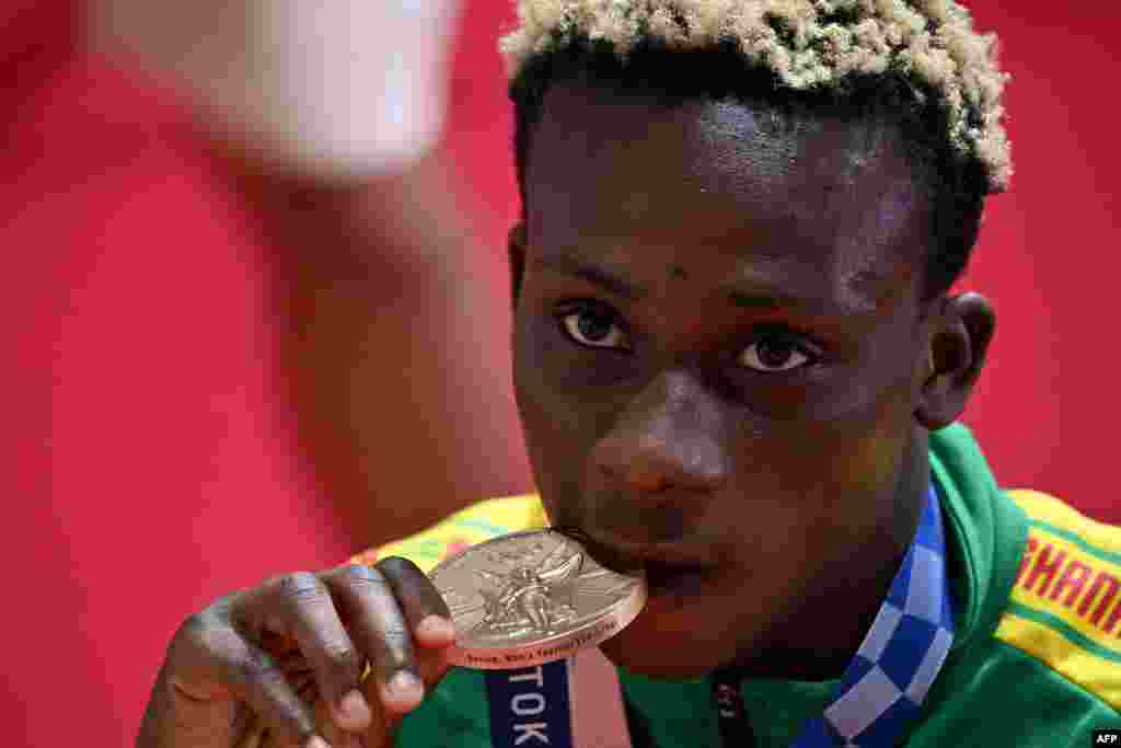 Bronze medallist Ghana&#39;s Samuel Takyi bites his medal on the podium after the men&#39;s feather (52-57kg) boxing final bout during the Tokyo 2020 Olympic Games at the Kokugikan Arena in Tokyo on August 5, 2021. (Photo by Luis ROBAYO / AFP)