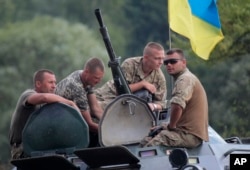 Ukrainian soldiers atop an APC watch training exercises under the supervision of British instructors on the military base outside Zhitomir, Ukraine, Aug. 11, 2015.