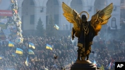 The Archangel Michael statue towers over pro-European Union activists during a rally in Independence Square in Kyiv, Ukraine, Saturday, Dec. 14, 2013.