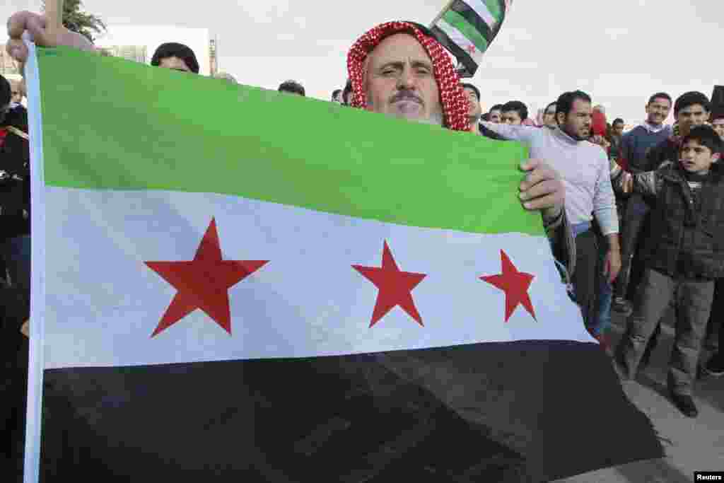 A Syrian protester living in Jordan holds up a Syrian opposition flag during a protest against Syria's President Bashar al-Assad, outside the Syrian embassy in Amman December 14, 2012. REUTERS/Muhammad Hamed (JORDAN - Tags: POLITICS CIVIL UNREST)