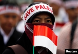 Một phụ nữ với biểu ngữ "Save Palestine" ("Hãy cứu Palestine") trong cuộc biểu tình ở Indonesia.