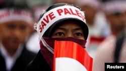 Seorang perempuan yang memegang bendera merah putih mengenakan ikat kepala bertuliskan "Selamatkan Palestina." Pemerintah mendukung keinginan Palestina untuk menjadi anggota penuh PBB.(Foto: Reuters)