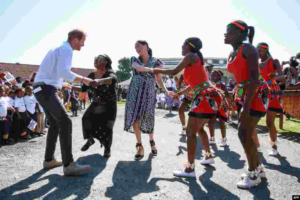 Prince Harry, Duke of Sussex and Meghan, Duchess of Sussex, dance during a visit to the &quot;Justice desk&quot;, an NGO in the township of Nyanga in Cape Town, as they begin their tour of the region.