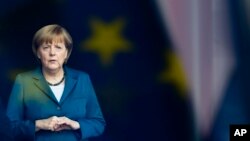 In this Monday, June 3, 2013 file photo, German Chancellor Angela Merkel stand behind a window with a reflection of the European flag as she waits for the arrival of King Willem-Alexander of the Netherlands at the chancellery in Berlin. (AP Photo/Markus S