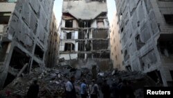 Palestinians gather near the remains of a building that was destroyed by an Israeli airstrike, in Gaza City, Nov. 13, 2018.