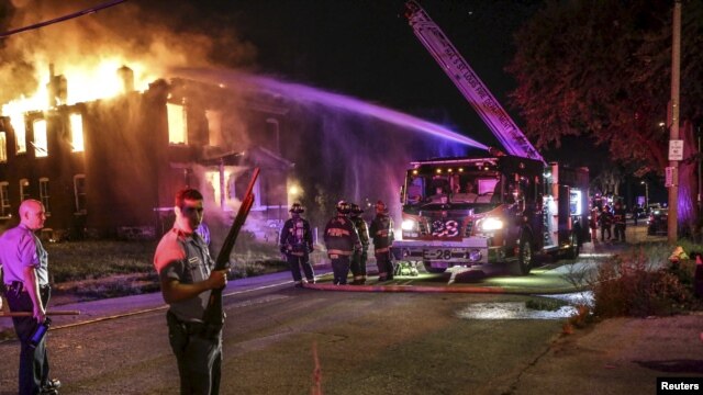 Bomberos intentan apagar un incendio en un edificio abandonado en San Luis, Missouri luego de las protestas por la muerte de un adolescente negro.