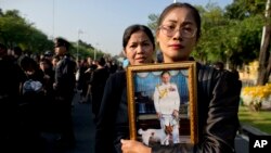 Thai mourners, carrying a portrait of late Thai King Bhumibol Adulyadej, gather in front of a replica of the royal crematorium in Bangkok, Thailand, Oct. 26, 2017.