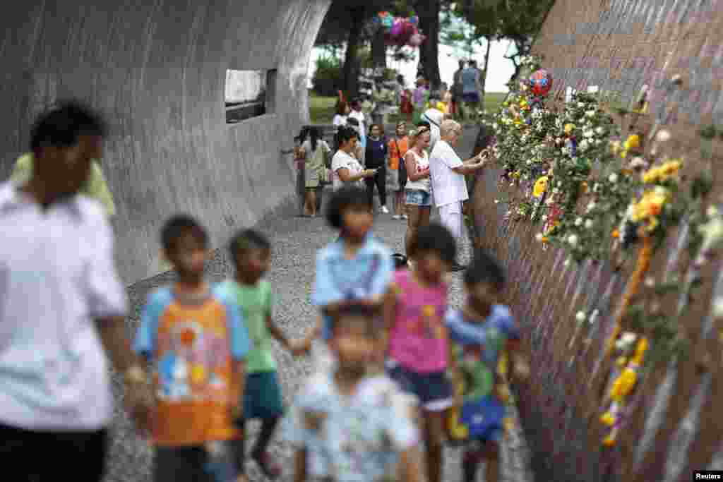 People pay their respects to the victims of the 2004 tsunami at a wave shaped memorial in Ban Nam Khem, a southern fishing village destroyed by the wave, December 26, 2014.