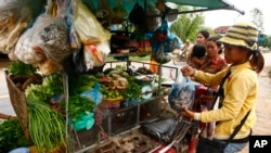 In this Tuesday, Oct. 1, 2013 photo, a vendor, right, holds a plastic bag containing salty fish at her mobile market, file photo. 