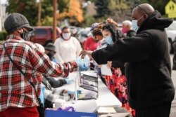 Relawan membagikan masker sebagai bagian dari program penjangkauan kepada komunitas kulit hitam untuk meningkatkan partisipasi uji coba vaksin di Rochester, New York, AS, 17 Oktober 2020. (Foto: Reuters)