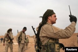 FILE - A Syrian Democratic Forces (SDF) fighter carries a walkie talkie as he stands with his fellow fighters during an offensive against Islamic State militants in northern Raqqa province, Syria, Feb. 8, 2017.