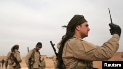 FILE - A Syrian Democratic Forces (SDF) fighter carries a walkie talkie as he stands with his fellow fighters during an offensive against Islamic State militants in northern Raqqa province, Syria February 8, 2017.