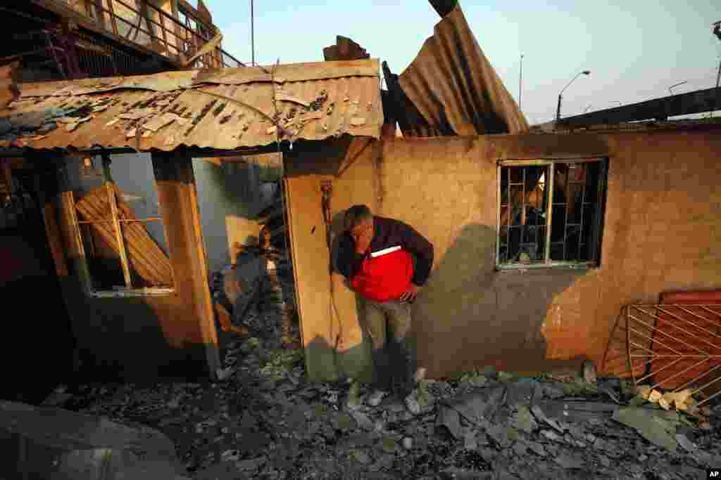 Um homem chora junto aos destroços da sua casa depois do incêndio florestal tê-la destruído, em Valparaiso, Chile, Abril 13, 2014.