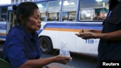 Pranom Chartyothin, a 72-year-old bus conductor, counts coins with a colleague after selling bus tickets in downtown Bangkok, Thailand, Feb. 3, 2016. 