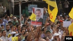 Protesters at a Muslim Brotherhood organized rally hold up a poster of ousted president Mohamed Morsi in Cairo, Sept. 27, 2013. (H. Elrasam for VOA)