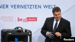 FILE - German Economy Minister Sigmar Gabriel is seen examining items at a technology summit in Berlin, Germany, Nov. 19, 2015.