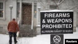 FILE - A man walks past a sign prohibiting firearms and weapons inside the State Legislature in Montpelier, Vermont, March 13, 2018.