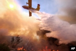 Un avión cisterna arroja agua sobre un incendio a lo largo de la autopista Ronald Reagan (118) en Simi Valley, California, el lunes 12 de noviembre de 2018. (Foto AP / Ringo H.W. Chiu)