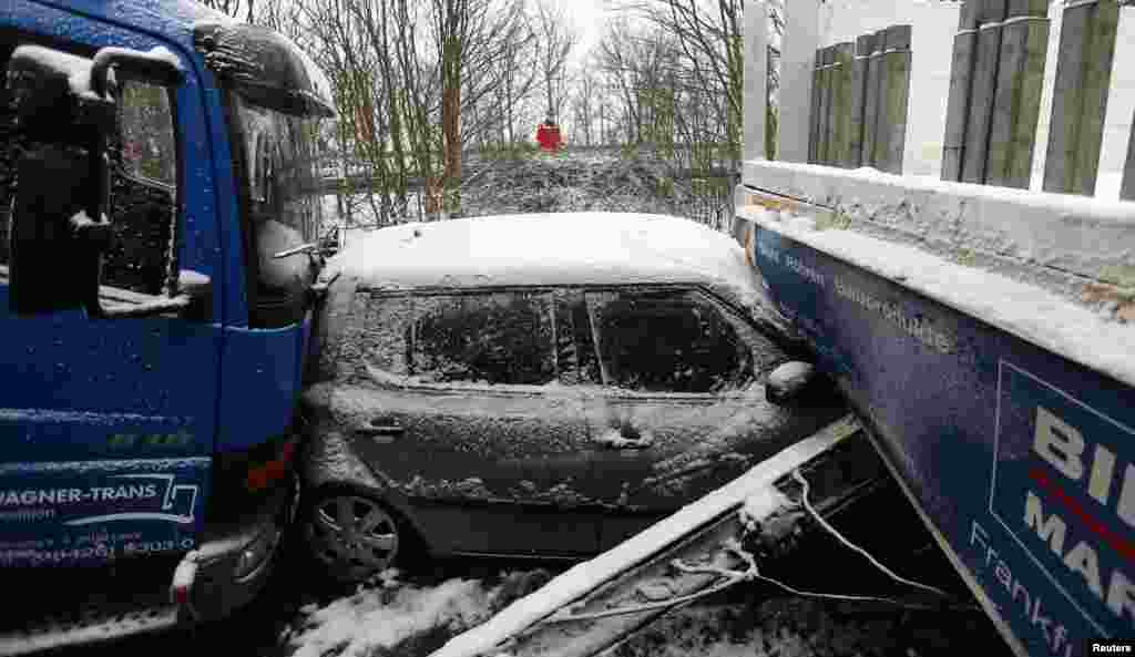 A rescue worker stands next to the wreckage of cars following an accident on highway A45 between Giessen and Hanau near the city of Woelfersheim, Germany. More than 100 cars were involved in a multiple pile-up after they crashed on the snowy highway, police at the scene said.