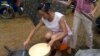 FILE - A child holds an umbrella as a Chinese woman tries to cook in the rain.