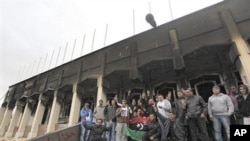 Libyan youth gather for a souvenir picture at the entrance to the burned house of Libyan Leader Moammar Ghadafi inside Al-Katiba military base, in Benghazi, Libya, February 27, 2011