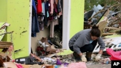 Leslie Harrington ayuda a una vecina a buscar alajas en su casa destruída tras una tormenta el domingo, 14 de abril de 2019, en las afueras de Hamilton, Mississippi.