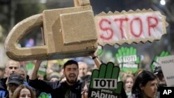 FILE - Protesters carrying a mock chainsaw and signs that read "All for the forests" march in Bucharest, Romania, Nov. 3, 2019. A large grouping of countries have agreed to improve protections for environmental defenders who risk abuse and harm because of their activism.