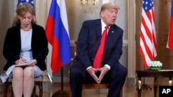 In this July 16, 2018 file photo interpreter Marina Gross, left, takes notes when U.S. President Donald Trump talks to Russian President Vladimir Putin at the beginning of their one-on-one-meeting at the Presidential Palace in Helsinki, Finland.