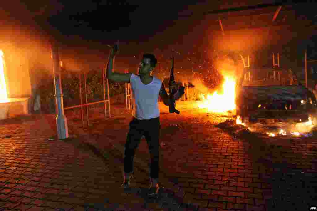 An armed man waves his rifle as buildings and cars are engulfed in flames after being set on fire inside the U.S. consulate compound in Benghazi, Libya, late on September 11, 2012. 